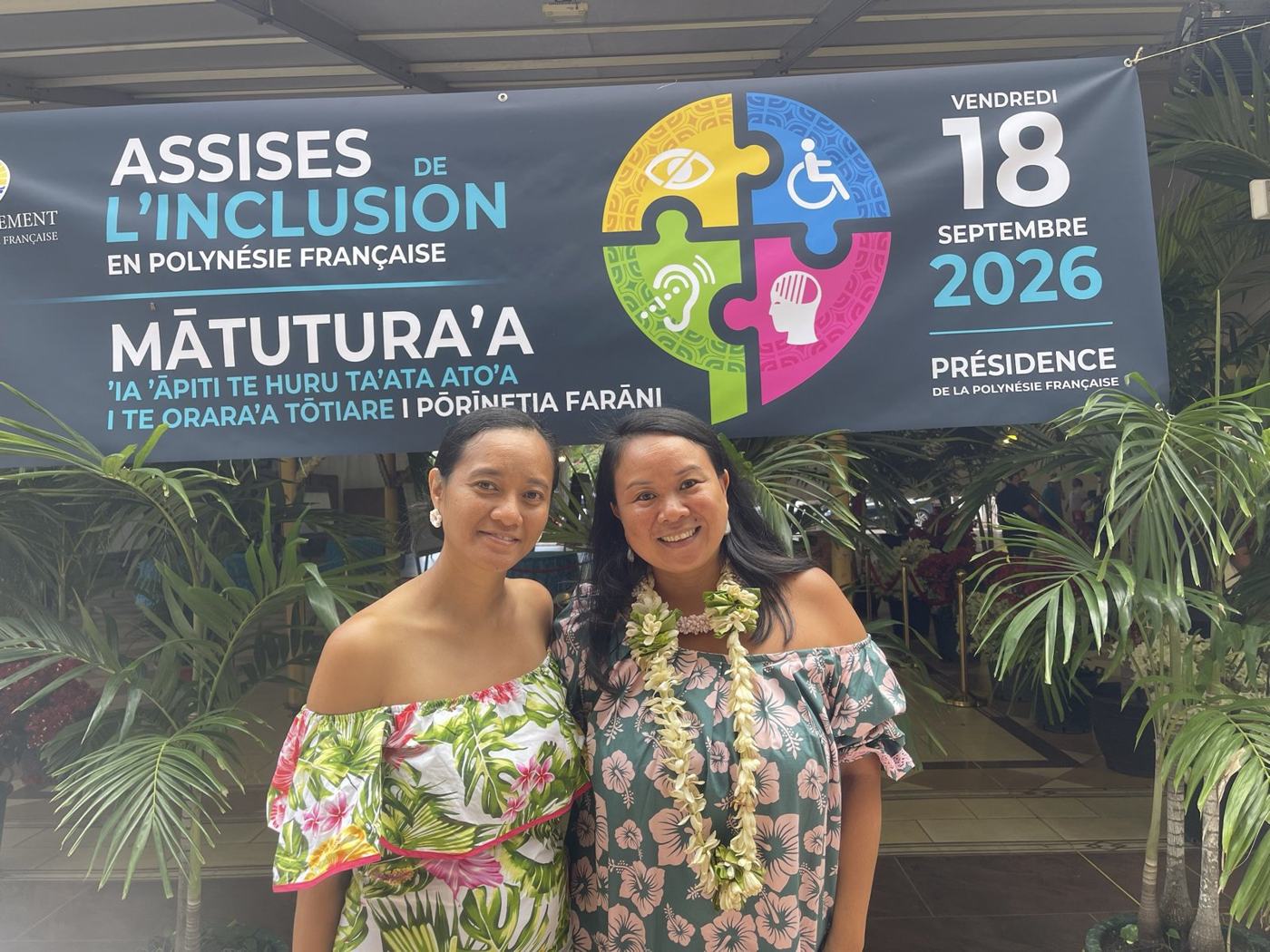 Deux femmes souriantes devant la banderole des Assises de l'inclusion