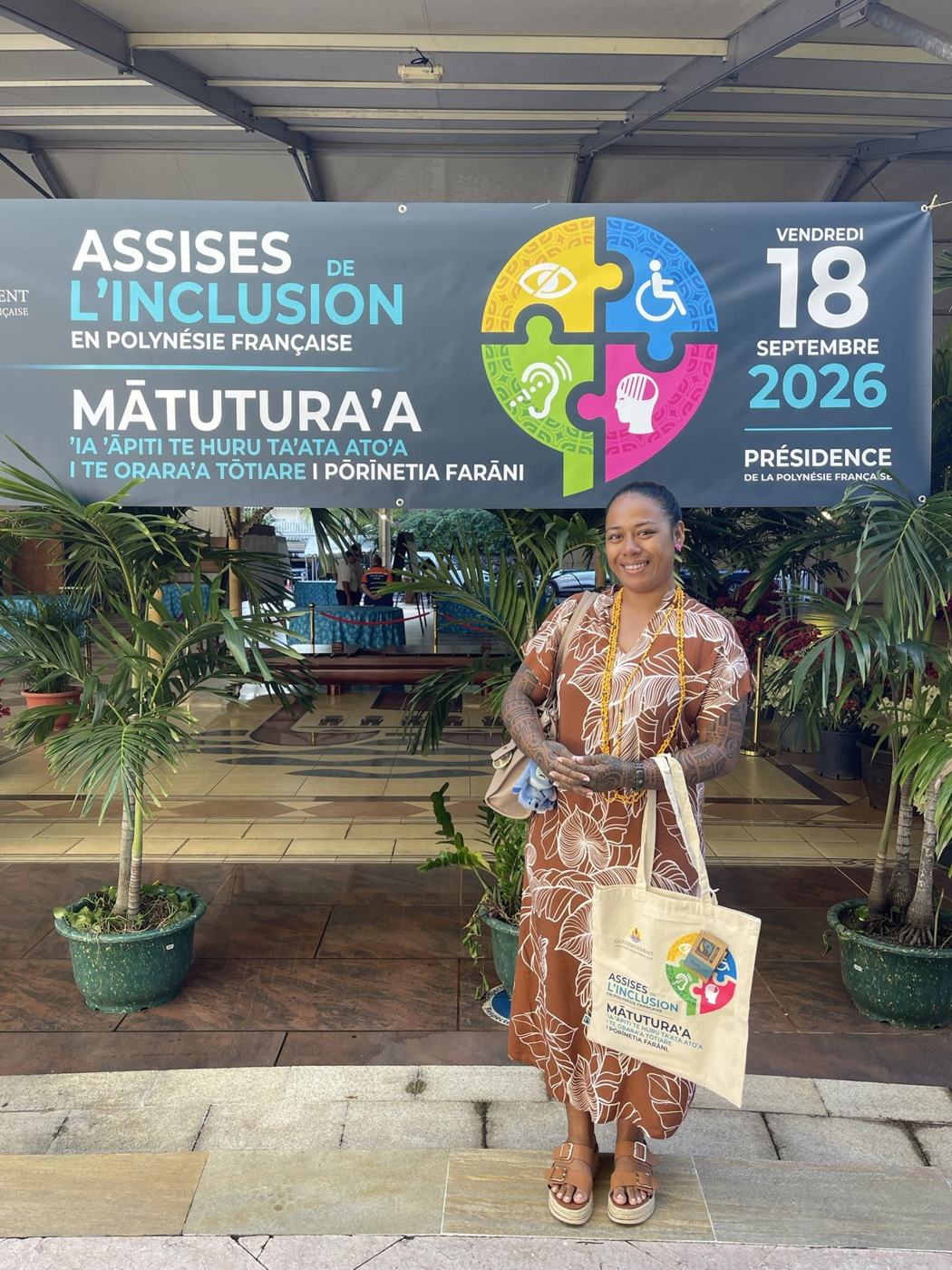 Une membre de l'association devant la banderole des Assises de l'inclusion