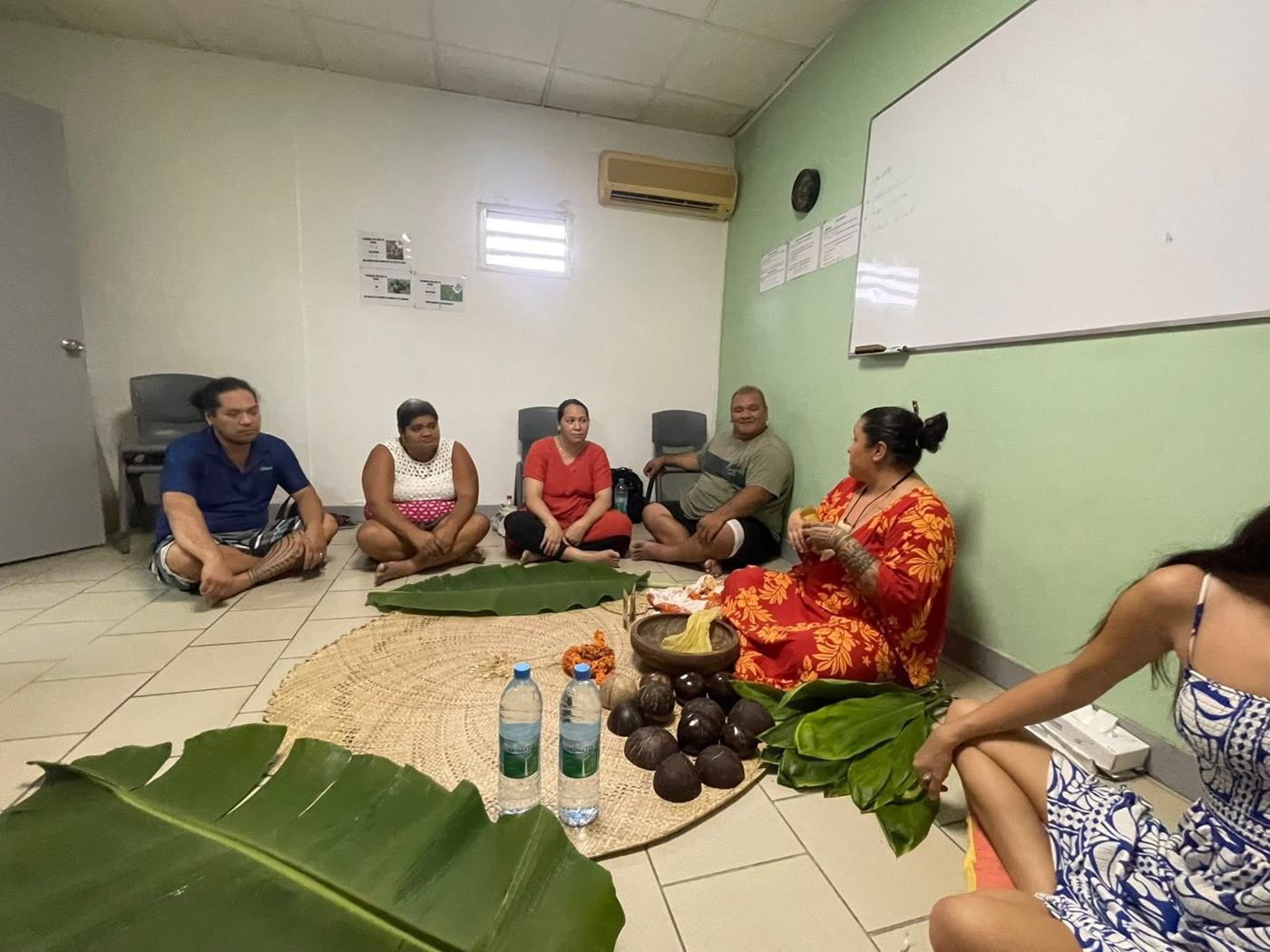 Participants assis en cercle autour du tapis tressé pendant la cérémonie du 'Ava