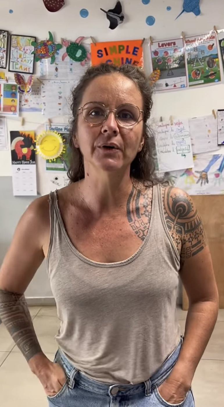 Line parle face caméra dans une salle de classe décorée de dessins d'enfants, à l'École bilingue