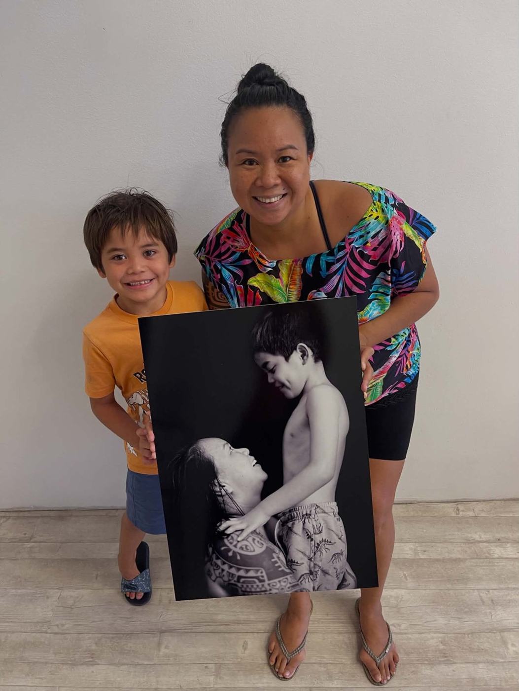 Augustine Roa et un enfant tenant un portrait en noir et blanc de l'exposition