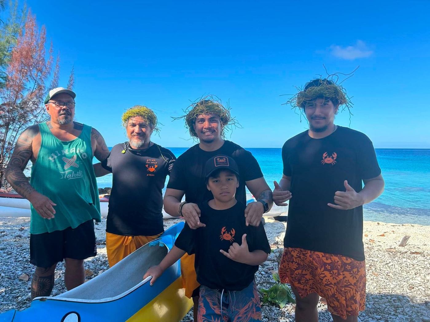 Rameurs et enfant en tee-shirts de l'association sur la plage, à côté d'une pirogue