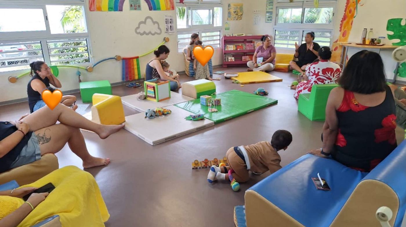 Parents assis en cercle dans une salle de jeux pour la petite enfance, pendant que les tout-petits jouent