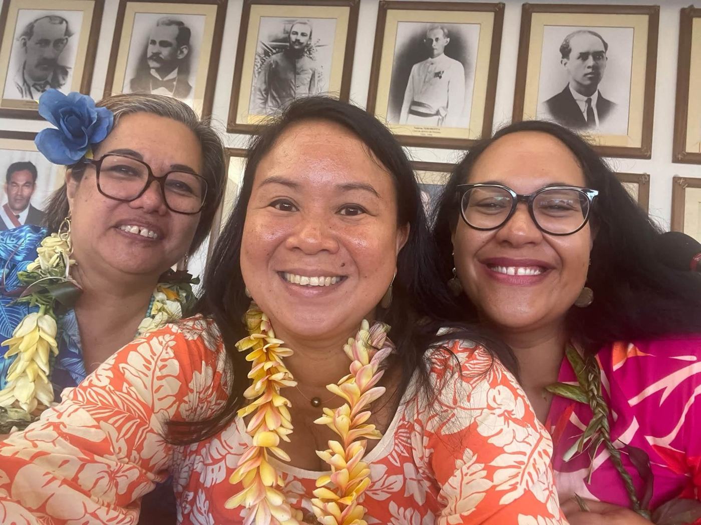 Trois femmes souriantes portant des colliers de fleurs à la mairie de Teva i Uta